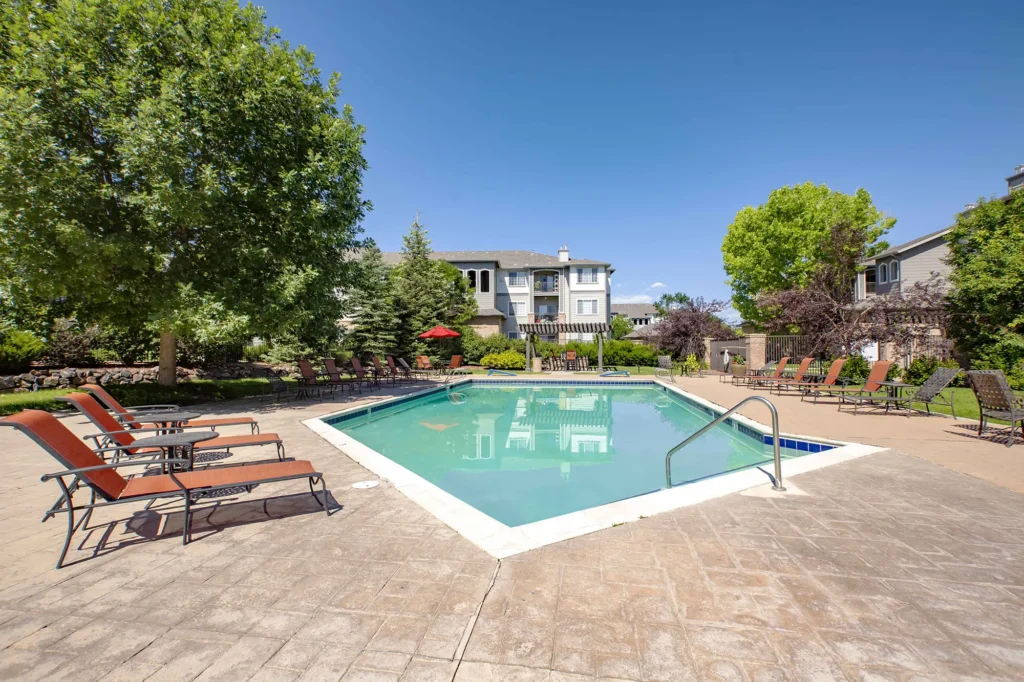 Swimming pool with shaded deck seating and large trees